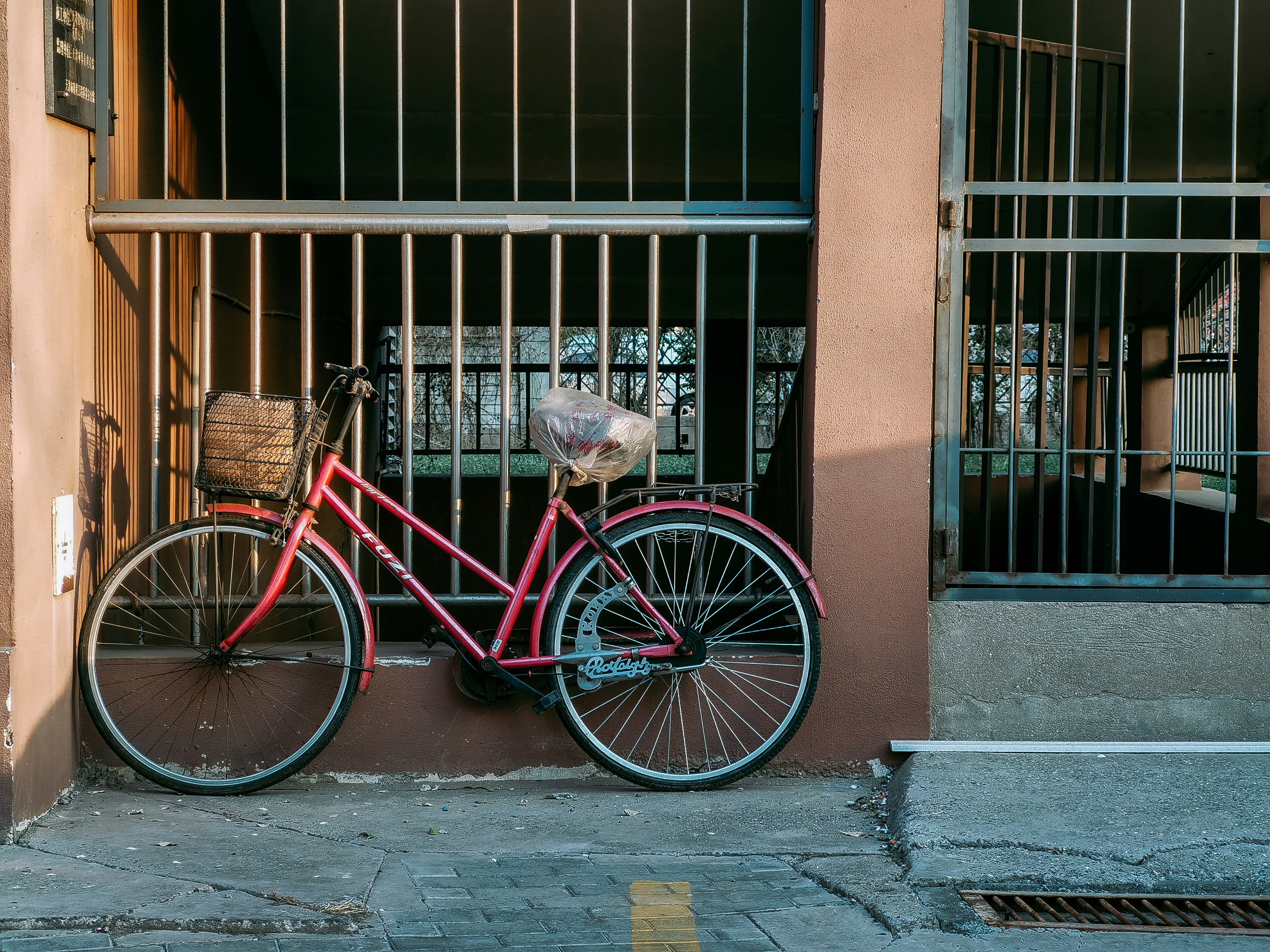 red city bike beside brown brick wall